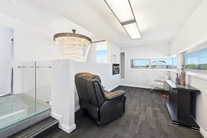 A modern room with a glass shower enclosure, a reclining chair, a desk with a computer, and a large window offering a view. - 4-Bed Retreat With Cinema in Wright (Wright)