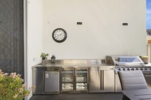 An outdoor kitchen with a stainless steel stove, a refrigerator, and a clock on the wall. - 4-Bed Retreat With Cinema in Wright (Wright)