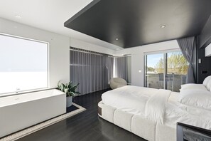A modern bedroom with a large bed, a seating area, and a view of the outdoors. - 4-Bed Retreat With Cinema in Wright (Wright)