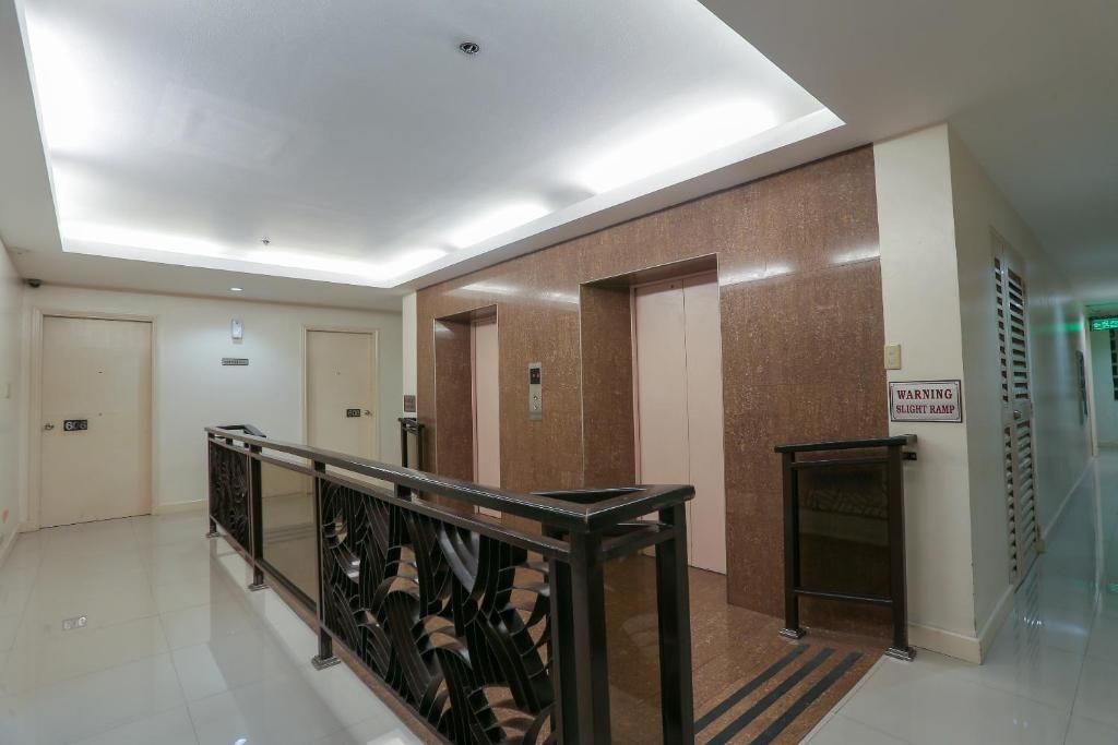 Un área de ascensor moderna con un letrero de advertencia, una barandilla de metal y un piso de baldosas.