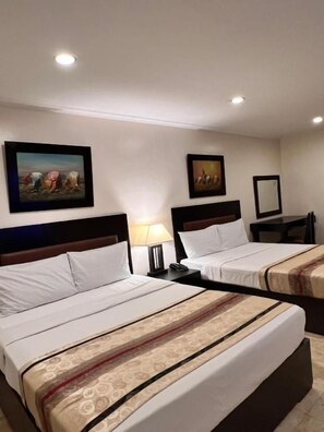 Habitación de hotel con dos camas, una mesita de noche, una lámpara y decoración en la pared.