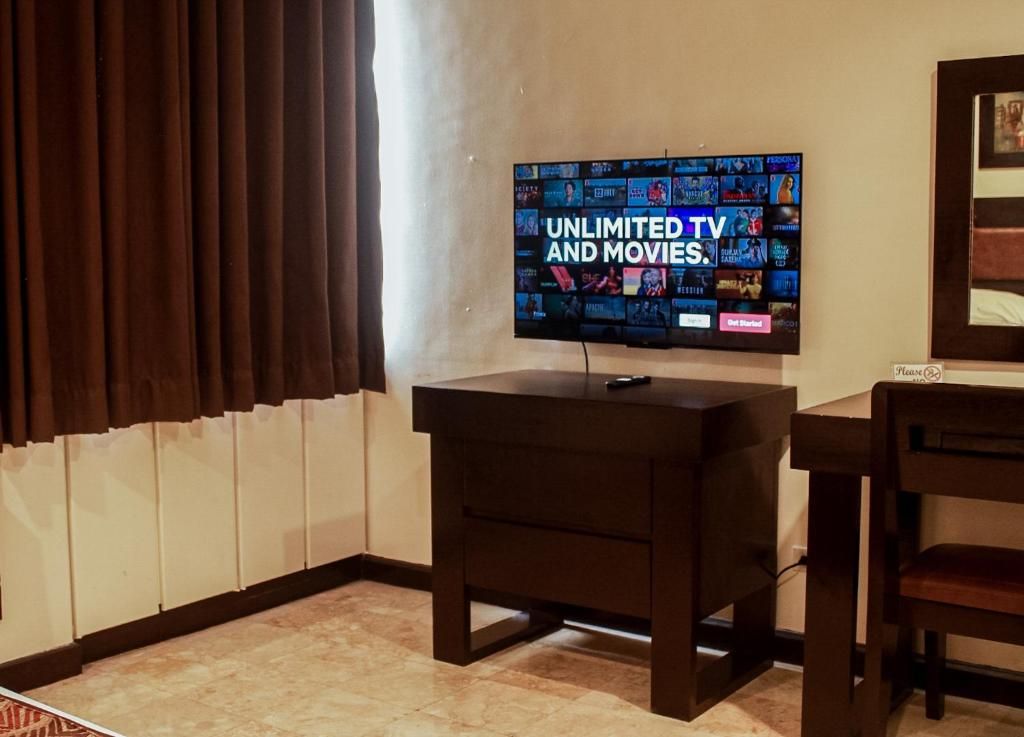 A room with a television displaying a selection of movies and TV shows, a dark wooden cabinet, and a chair.