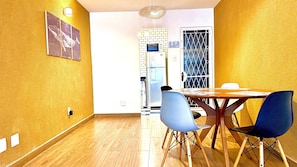 Ein Essbereich mit einem Holztisch, blauen Stühlen und einer Wand mit Muster.