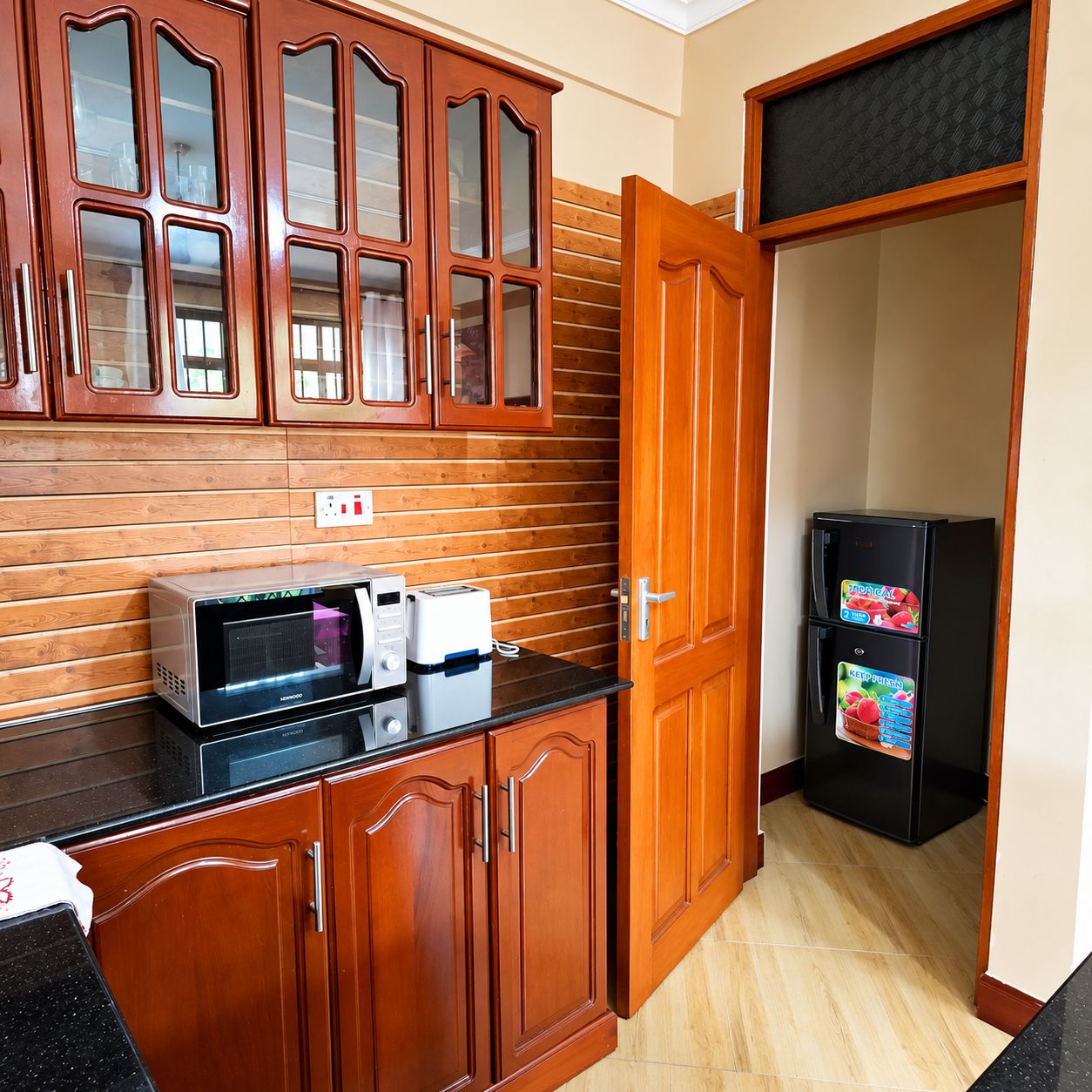 Una cocina con gabinetes de madera, microondas, tostadora y refrigerador.