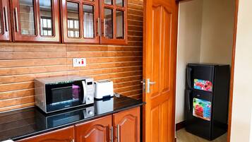 Una cocina con gabinetes de madera, microondas, tostadora y refrigerador.