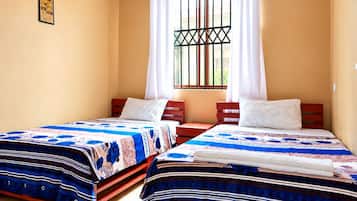 A room with two beds, a window with curtains, and a picture on the wall.