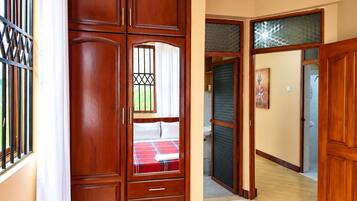 A bedroom with a bed, a wardrobe, and a bathroom visible through an open door.