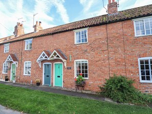 A red brick cottage with two doors, a small garden, and a clear sky. - Marmaduke Cottage (York)