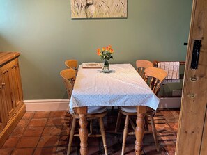 Ein Essbereich mit einem Tisch, der mit einer gemusterten Tischdecke bedeckt ist, umgeben von Holzkästen.