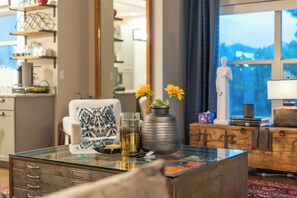 Ein modernes Wohnzimmer mit einem Glastisch, einem weißen Sessel und einer Vase mit Blumen.