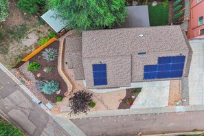 A residential property with a sloped roof, solar panels, and a landscaped garden with various plants and a small tree. - Red Rock Retreat | Hot Tub, EV Charger & Office (Colorado Springs)