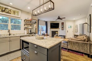 A modern kitchen with granite countertops, a built-in oven, and a dining area with a sofa and coffee table. - Red Rock Retreat | Hot Tub, EV Charger & Office (Colorado Springs)