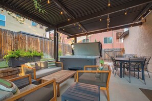 Une terrasse extérieure équipée d’un barbecue, de sièges et offrant une vue sur le jardin arrière.