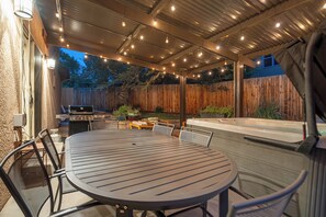 An outdoor patio with a round table and chairs, a grill, and a hot tub. - Red Rock Retreat | Hot Tub, EV Charger & Office (Colorado Springs)