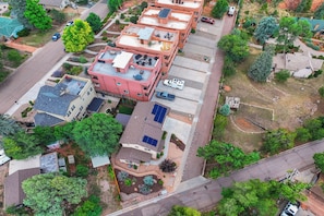 An aerial view of a residential area with multiple buildings, including a pink house with a rooftop patio and solar panels. - Red Rock Retreat | Hot Tub, EV Charger & Office (Colorado Springs)