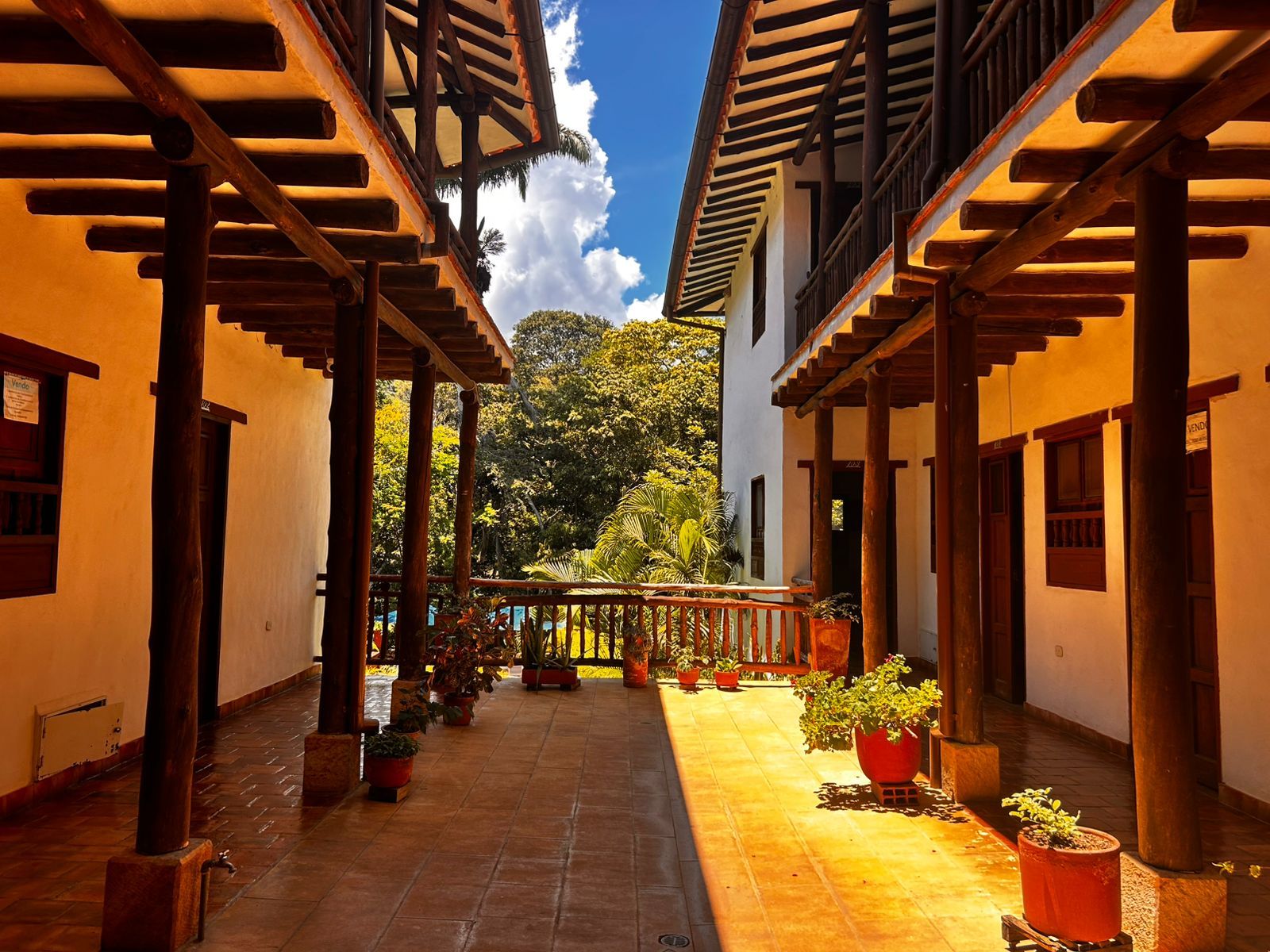 A courtyard with a tiled floor, wooden pergolas, and potted plants.