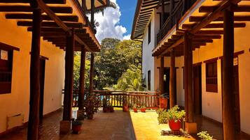A courtyard with a tiled floor, wooden pergolas, and potted plants.