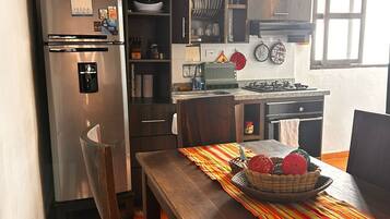 Una cocina con refrigerador, estufa y mesa de comedor con sillas.