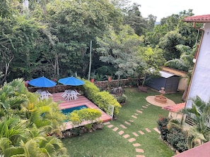Un exuberante jardín con piscina, mobiliario de exterior y una fuente.