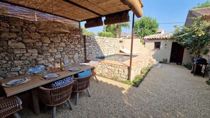 Eine Steinsäule, ein Tisch mit Stühlen, ein Grill und ein kleiner Pool.
