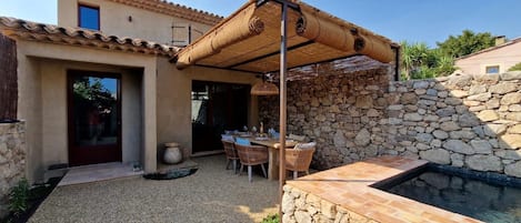 A patio area with a stone wall, a seating arrangement, and a small pool.