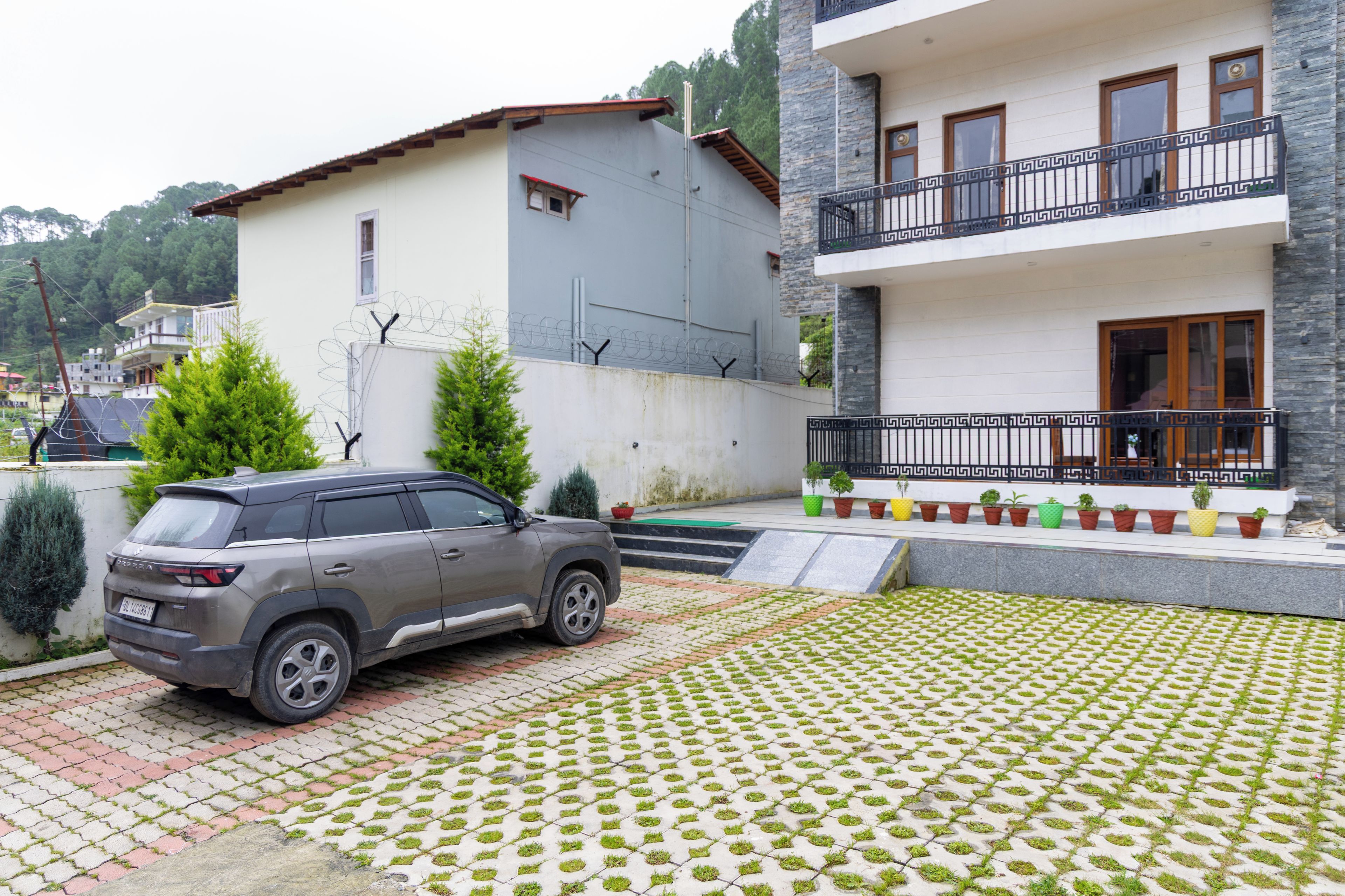 Un edificio residencial con un SUV gris estacionado frente a él.