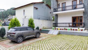 Un edificio residencial con un SUV gris estacionado frente a él.