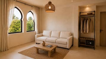 A living room with a sofa, a coffee table, a hanging light fixture, a window with curtains, and a clothing rack.