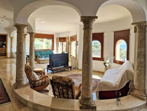 A spacious living area with a fireplace, seating, and large windows. - Romantic designed stone house with pool & views (Palau-Saverdera)