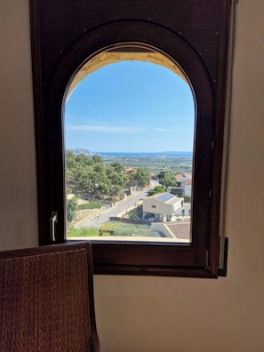A room with a view through a window, featuring a chair and a door. - Romantic designed stone house with pool & views (Palau-Saverdera)