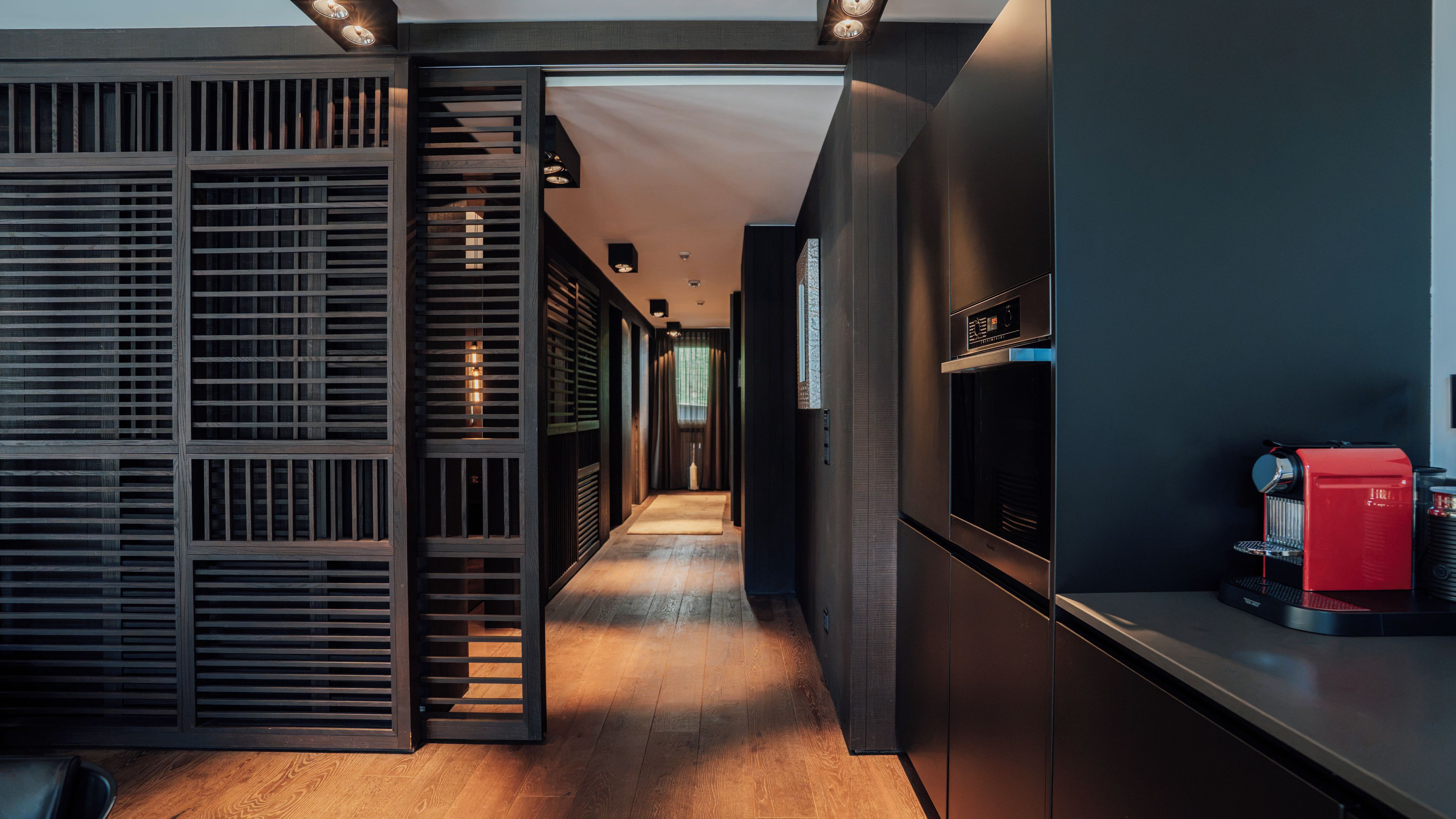 A modern kitchen with a built-in espresso machine and a wooden floor.
