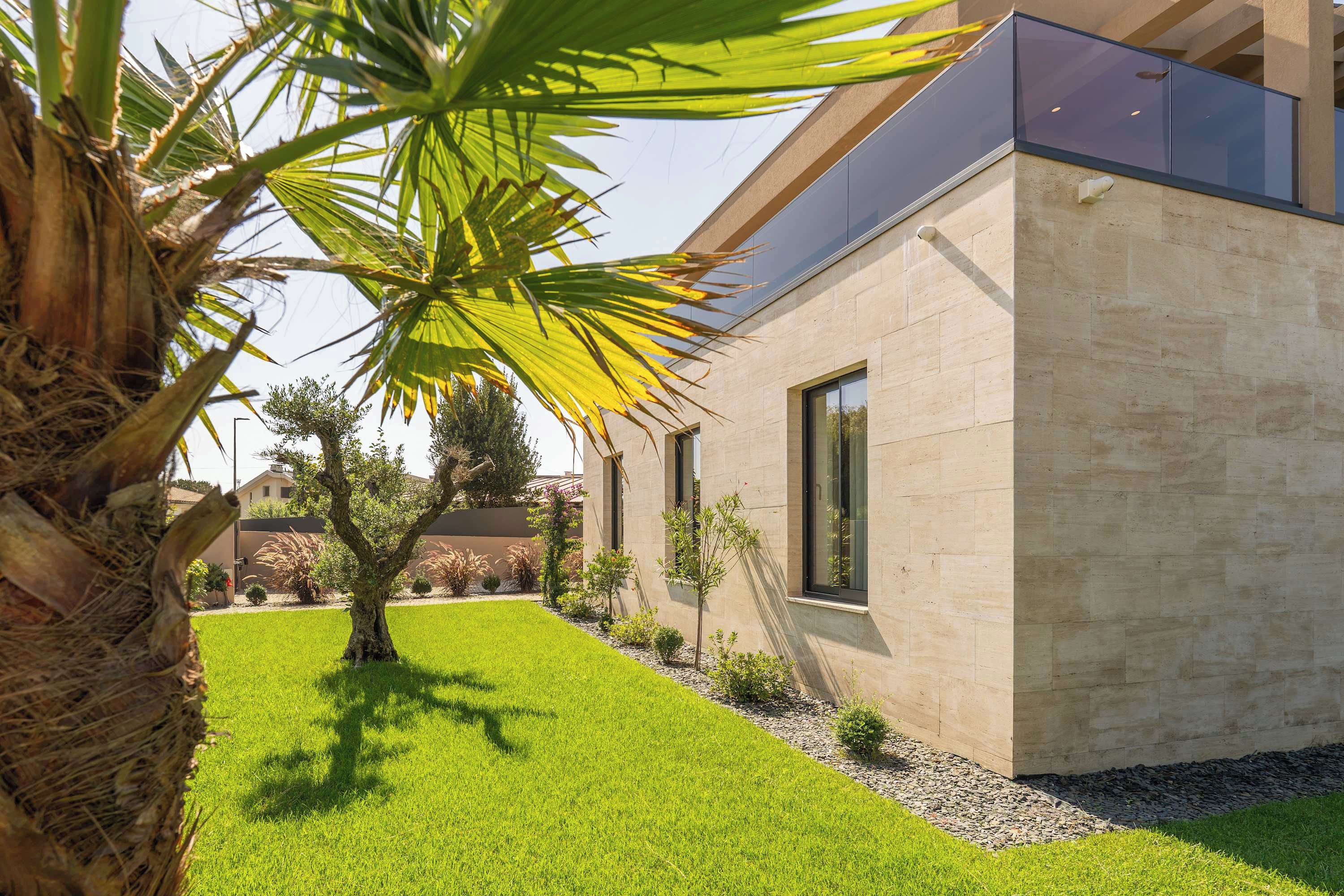 A modern building with a flat roof, large windows, and a well-maintained lawn.