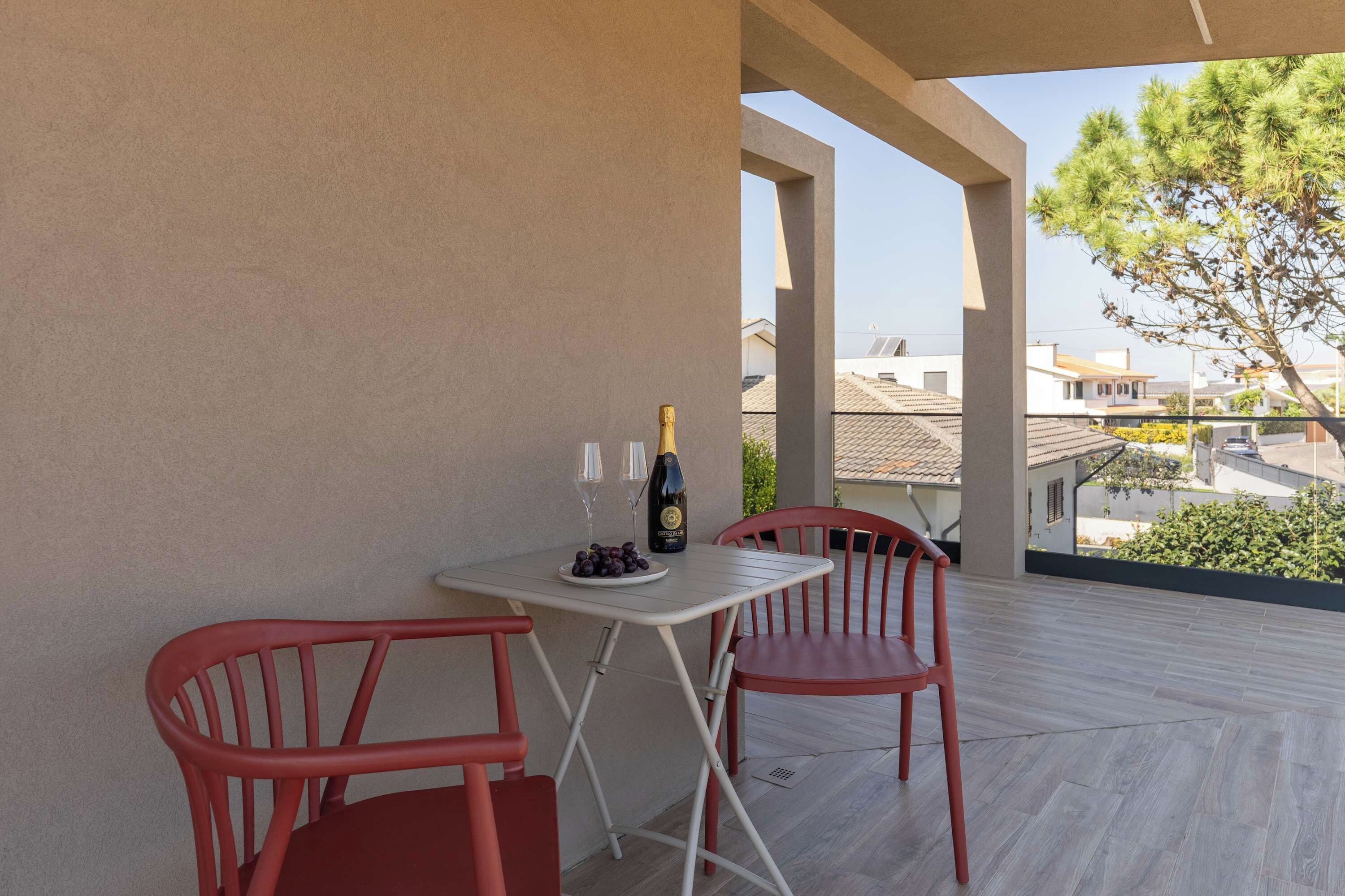 A balcony with a table and two chairs, a bottle of wine, and a glass.