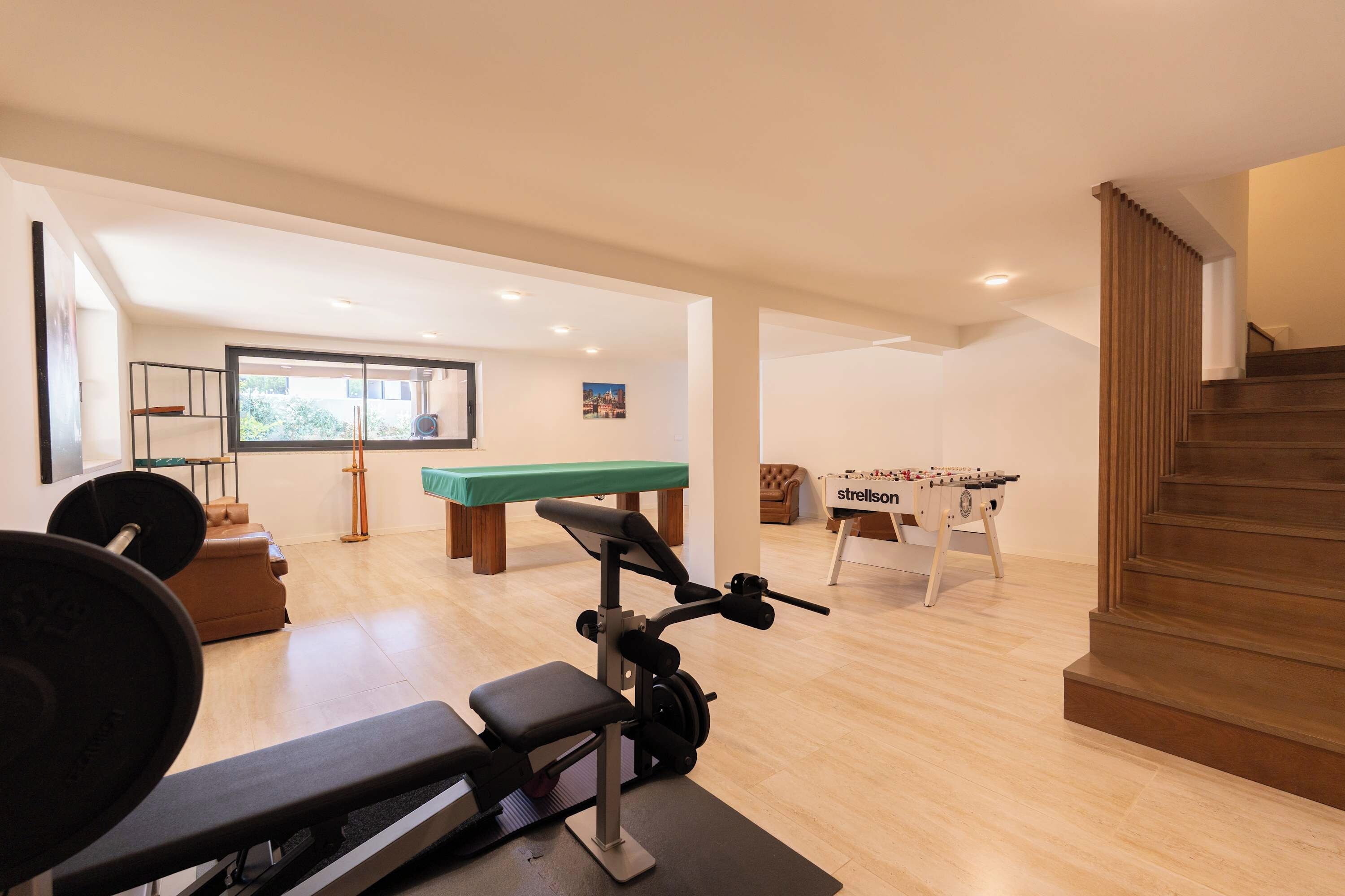 Un gimnasio con equipamiento de ejercicio, mesa de billar y mesa de fútbol de mesa.