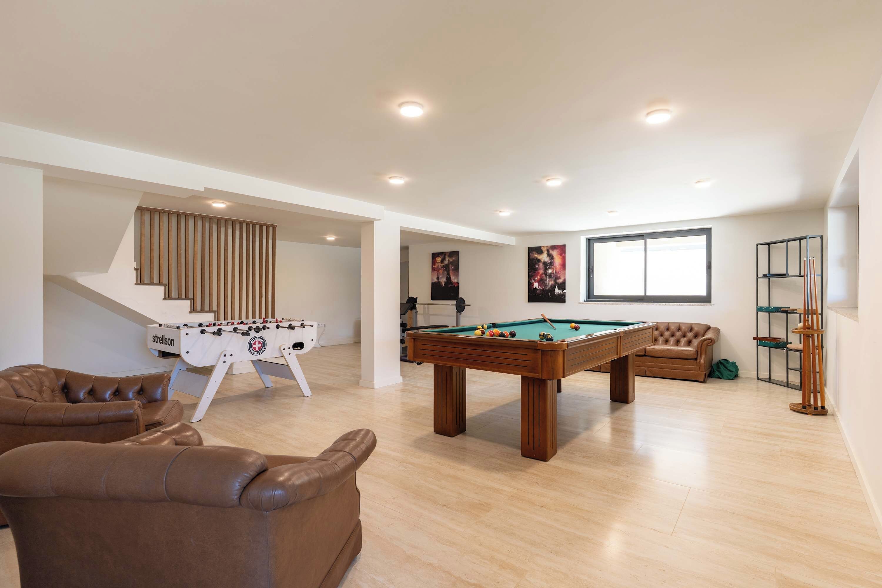 A spacious living area with a foosball table, pool table, and a sofa.
