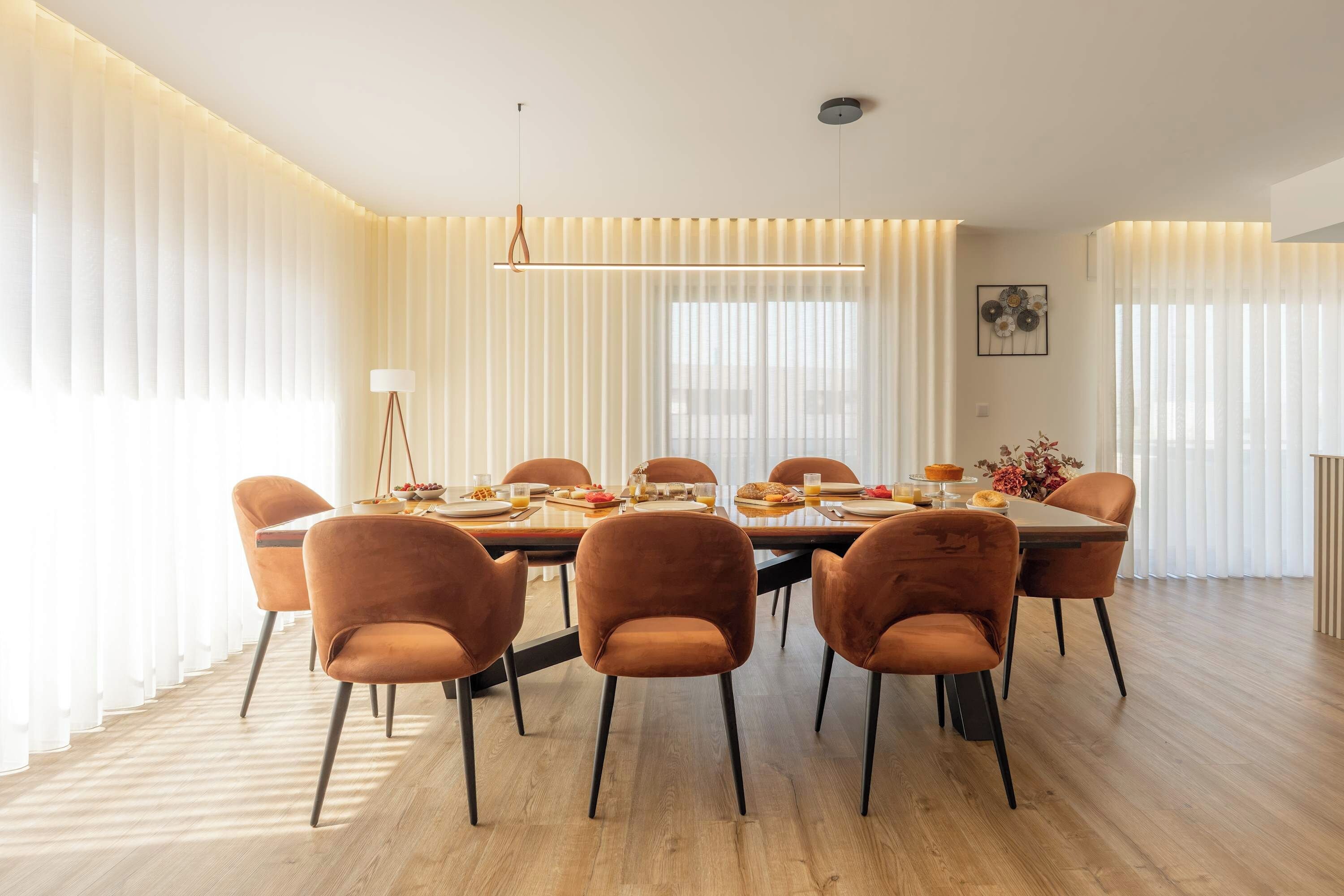 Un comedor moderno con una mesa larga, seis sillas y una lámpara colgante.