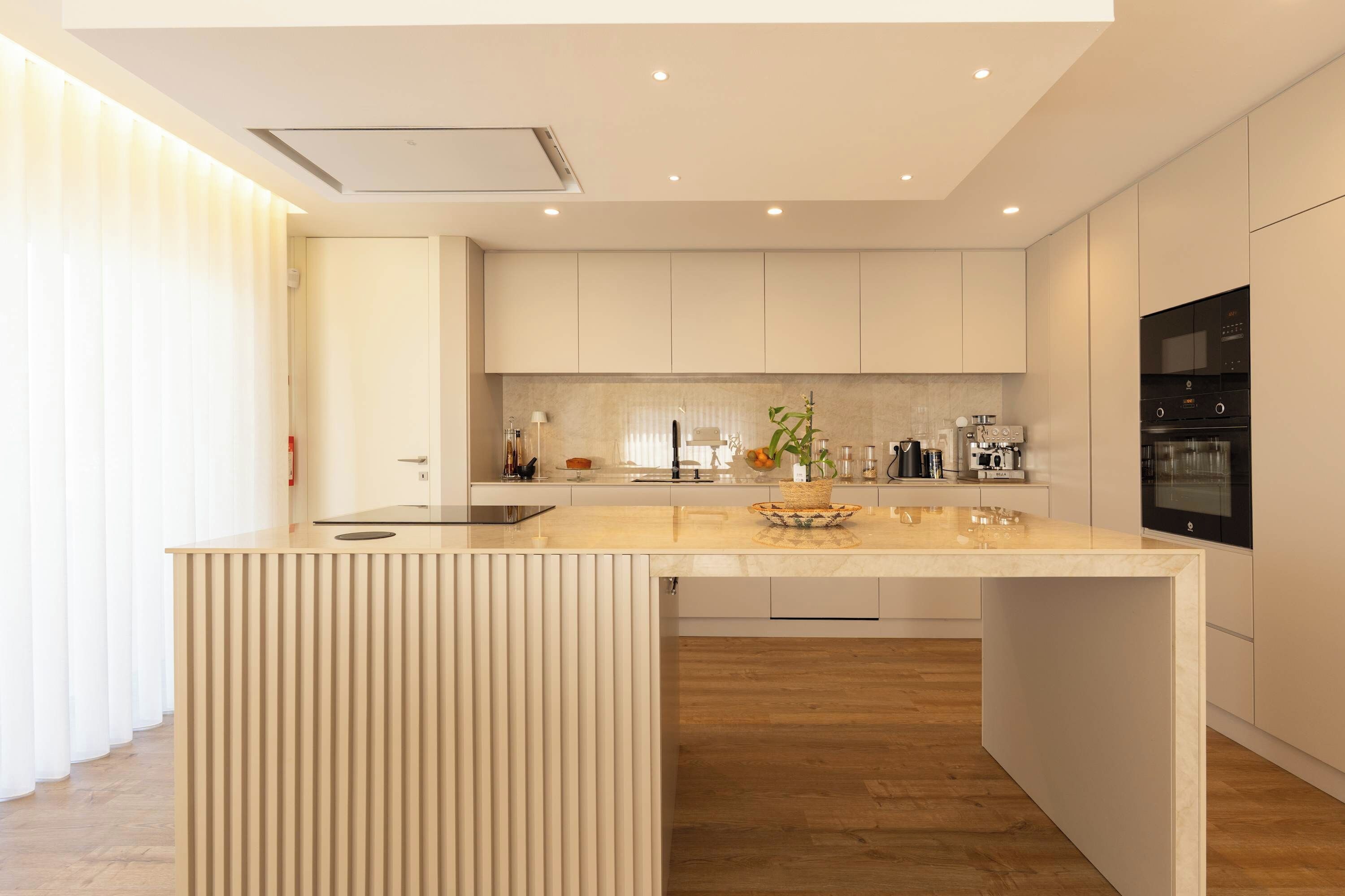 Una cocina moderna con una isla central, muebles blancos y electrodomésticos integrados.