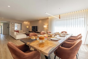 Una sala de estar moderna con comedor, sofá, televisor y lámpara.