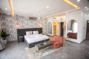 Una camera da letto moderna con un letto, comodini, un'area salotto e cabina armadio.