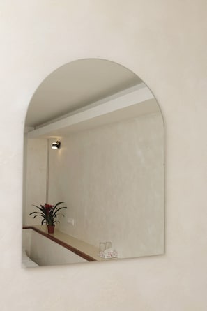 Un espejo con arco que refleja una escalera, una planta en maceta y una caja de pañuelos.