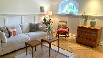 A living room with a sofa, a wooden coffee table, a chair, a dresser, and a window with a view.