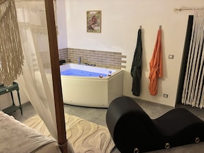 Una camera da letto con una vasca da bagno ampia, un letto a baldacchino e un portasciugamani montato a parete.