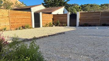 A residential property with a gravel driveway, wooden fences, and a gate.