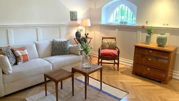 A living room with a sofa, a wooden coffee table, a chair, a dresser, and a window with a view.