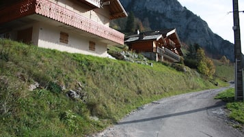 Un chalet traditionnel doté d’un balcon, situé dans un cadre montagneux.