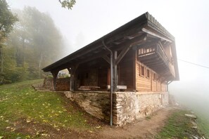 Une cabane en bois rustique, avec des fondations en pierre, une véranda et une cheminée.