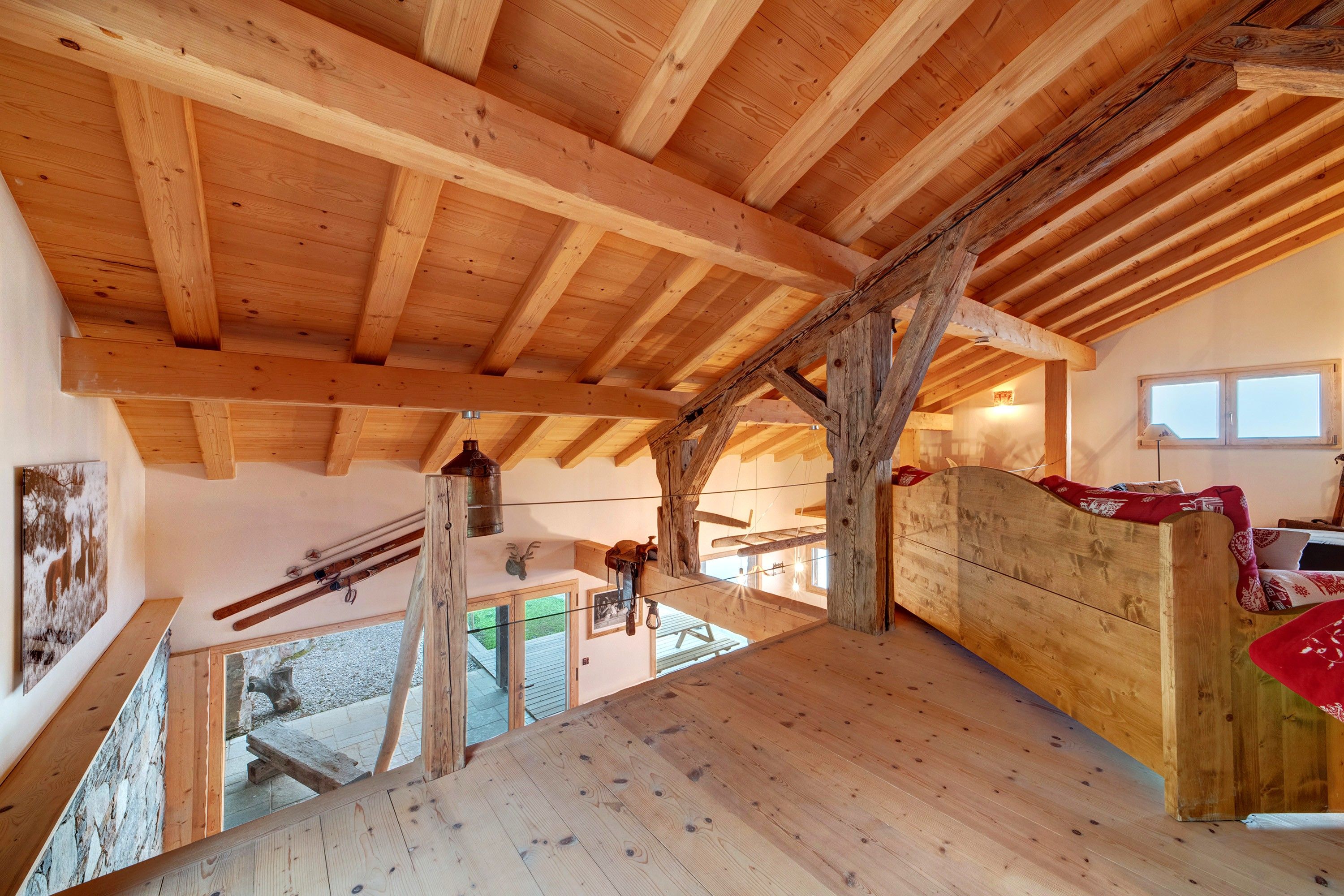 Un intérieur en bois avec un plafond en pente, des poutres apparentes et une vue sur l’extérieur.