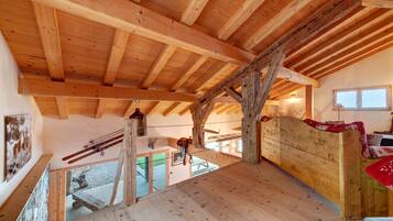 Un intérieur en bois avec un plafond en pente, des poutres apparentes et une vue sur l’extérieur.
