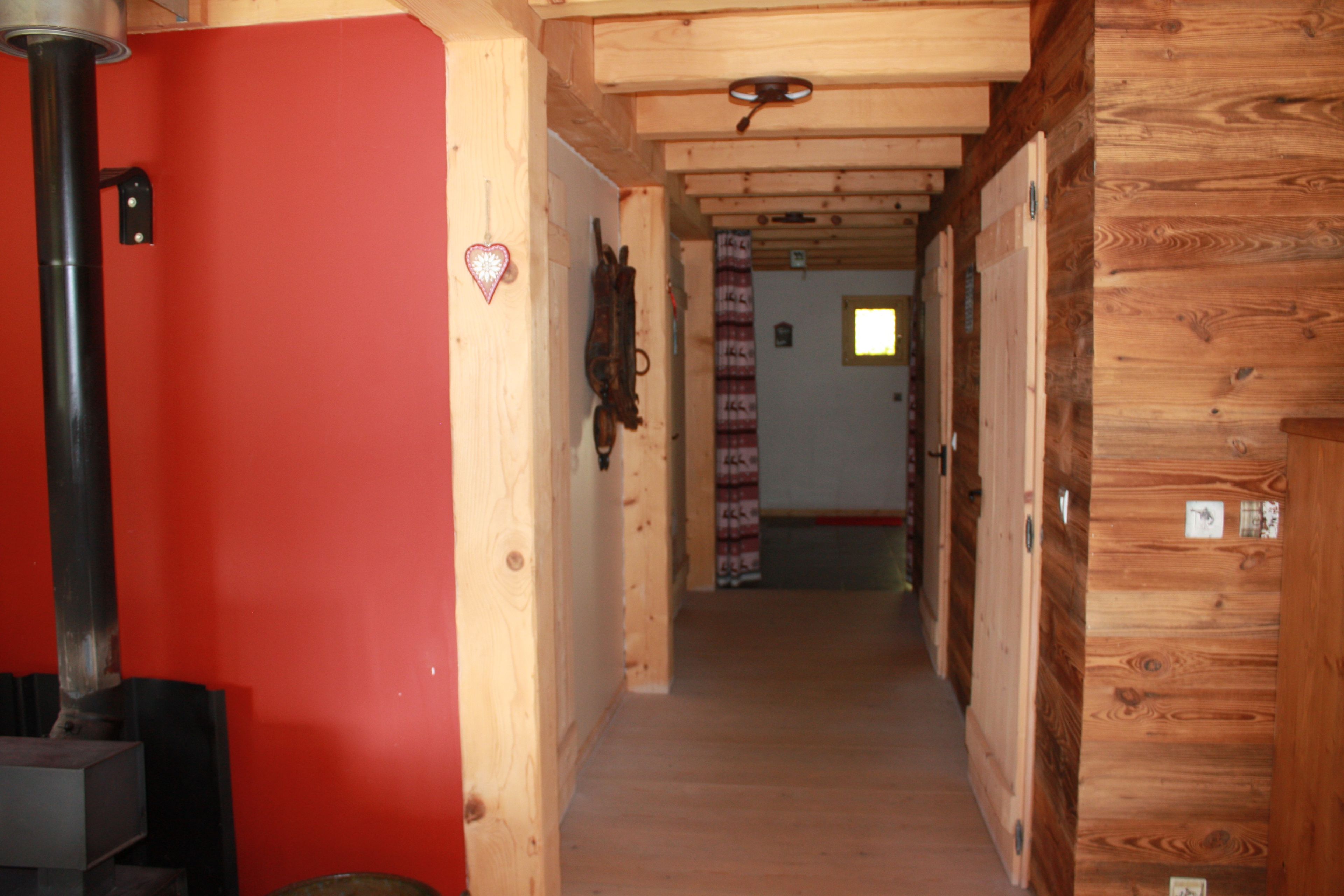 Un corridoio con pareti in legno e una porta rossa, che conduce a una stanza con una finestra e una porta.
