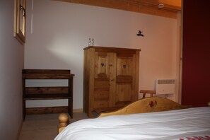Un dormitorio con una cama de madera, un armario de madera, un taburete pequeño de madera y un radiador blanco.